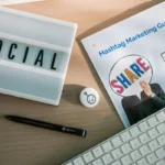 Meja kerja dengan peralatan pemasaran media sosial termasuk keyboard dan panduan strategi